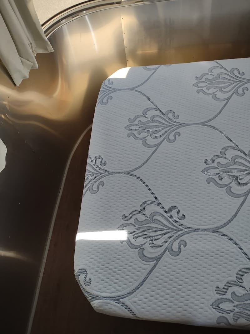 Quilted mattress cover against the curved wall of an Airstream